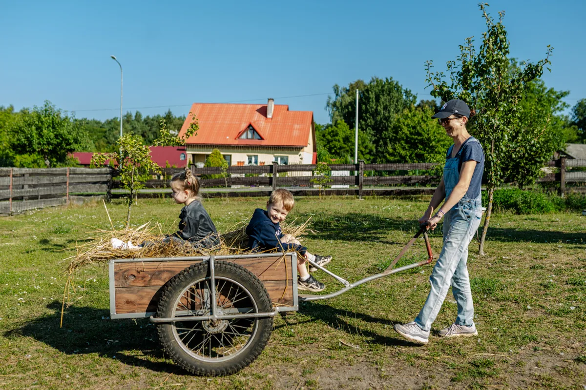 Gospodyni ciągnąca wózek ze słomą i dwójką dzieci