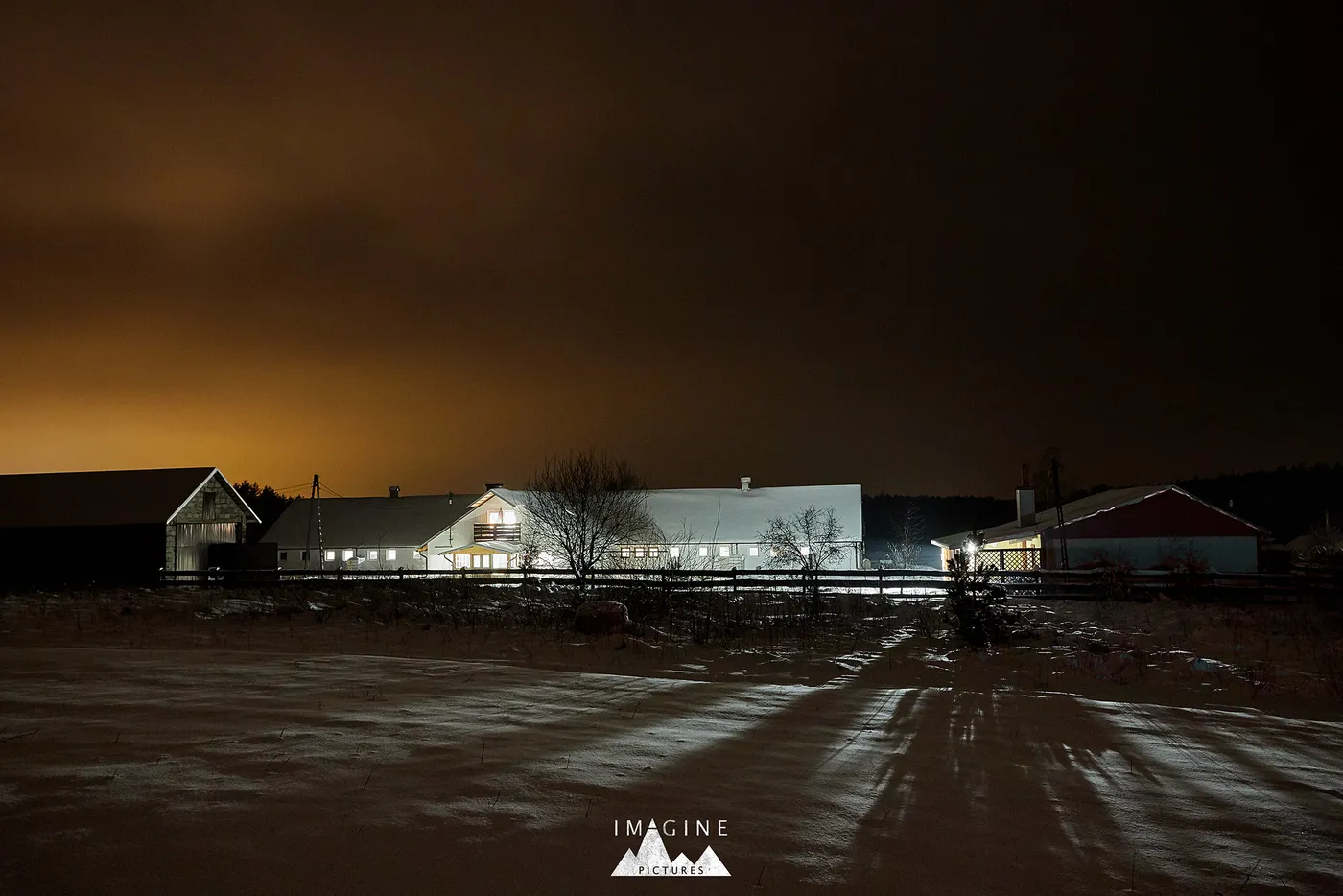 Rozświetlone zabudowania gospodarstwa zimową nocą