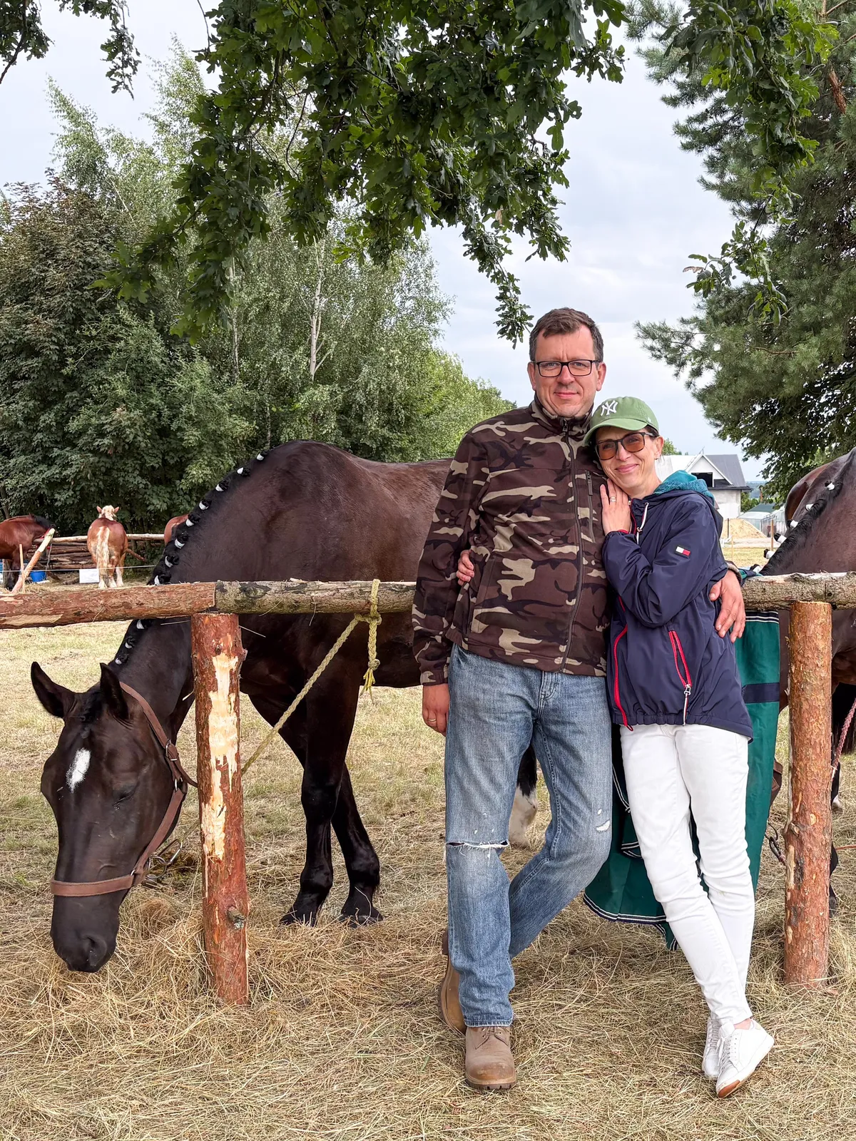 Przemek i Ewa przy drewnianym ogrodzeniu padoku, obok kara klacz
